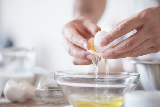 Hands carefully separating egg yolks and whites into a bowl, perfect for culinary content.